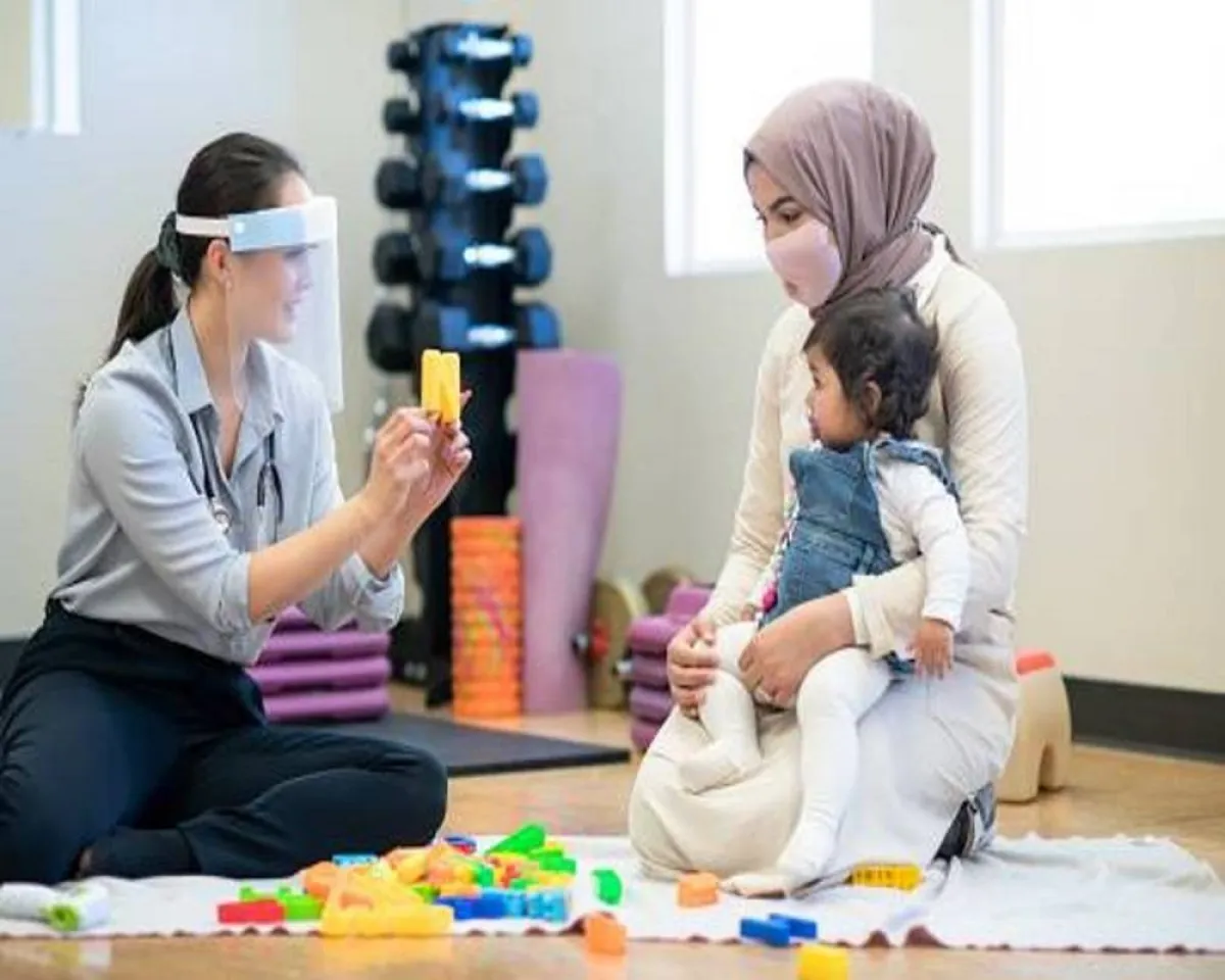 صورة لطبيبة تحاول تعليم الطفل مهارات النطق