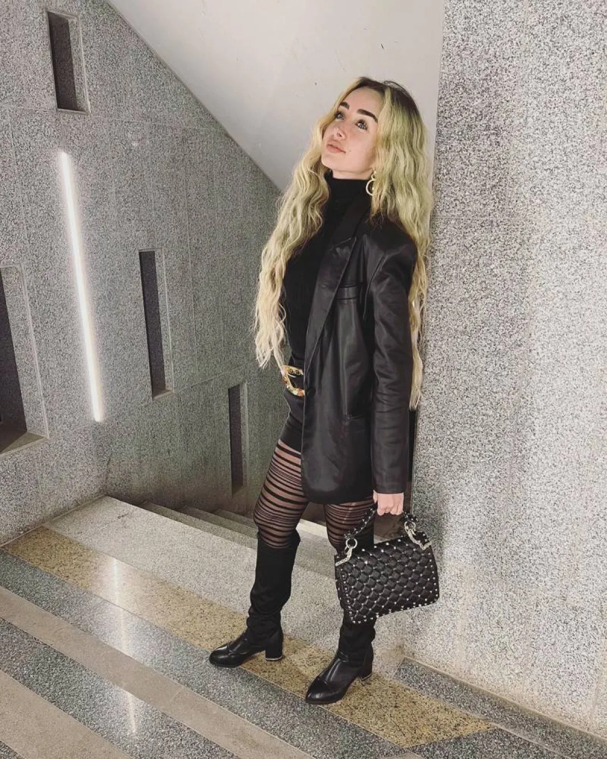 هنا الزاهد بمعطف جلد قصير أسود وهوت شورت وتوب برقبة عالية باللون الأسود