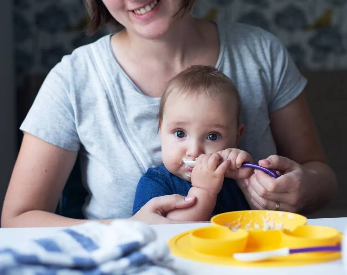 صورة لأم فرحة بقبول رضيعها للطعام الخارجي