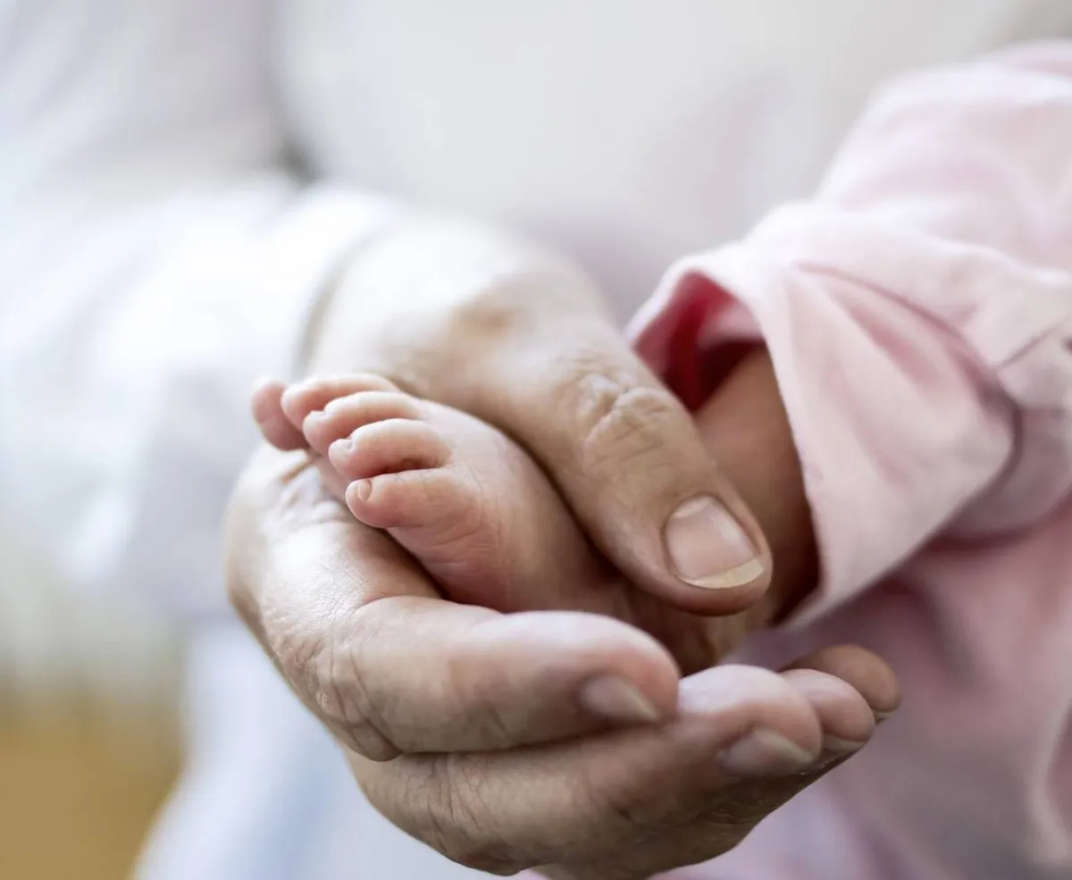 صورة تعبيرية للجدة تمسك بقدم المولود