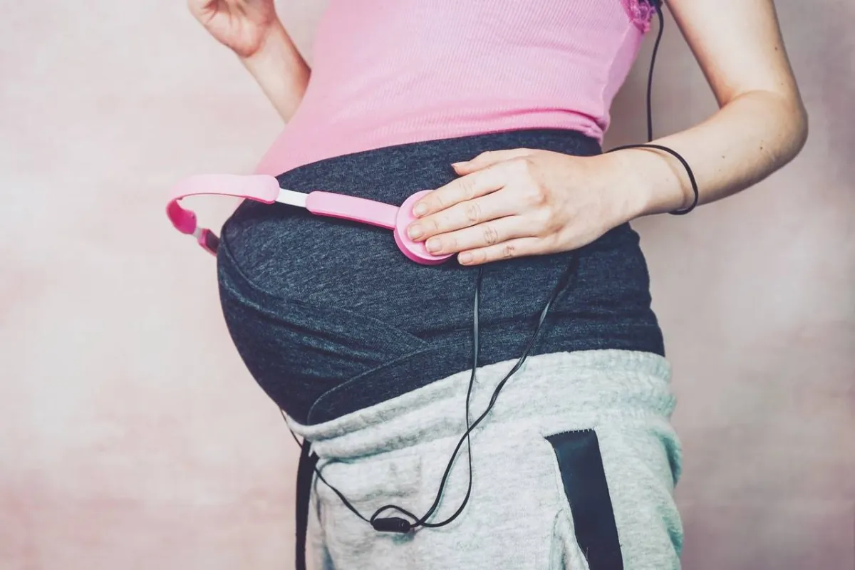 صورة لحامل تستمع لركلات جنينها