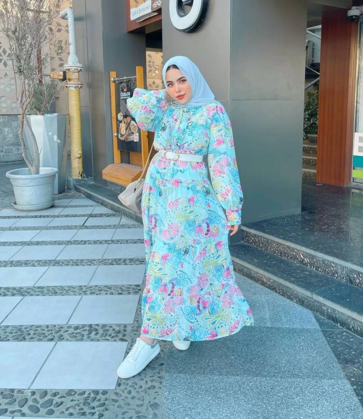 مي محمد بفستان أزرق مُطبع بالورود وحقيبة كتف رمادي