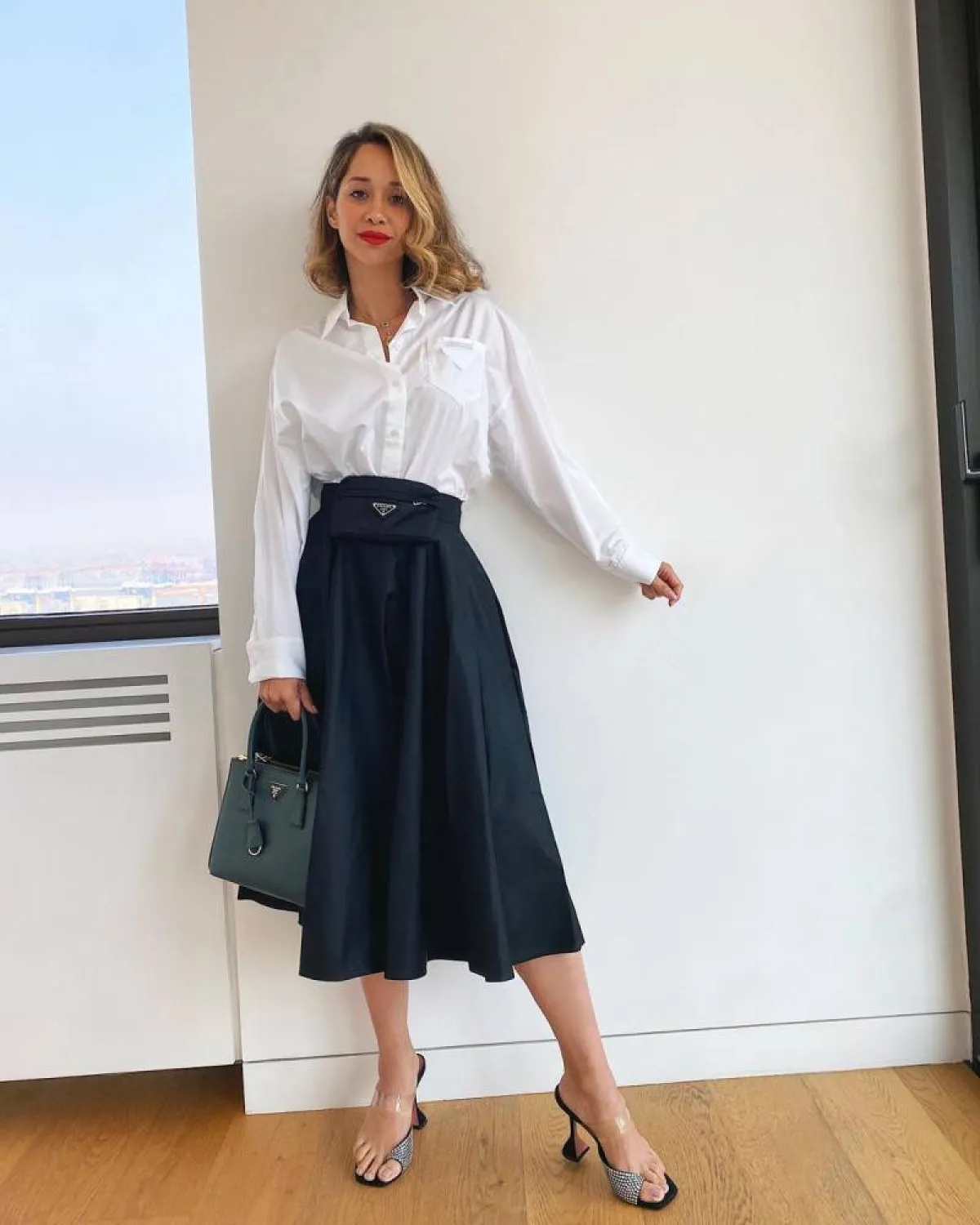 لانا الساحلي بقميص أبيض وتنورة ميدي سوداء وحقيبة خضراء من برادا