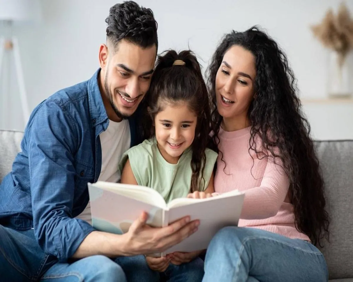 صورة لأم مع زوجها وطفلتها يتصفحون ألبوم الذكريات