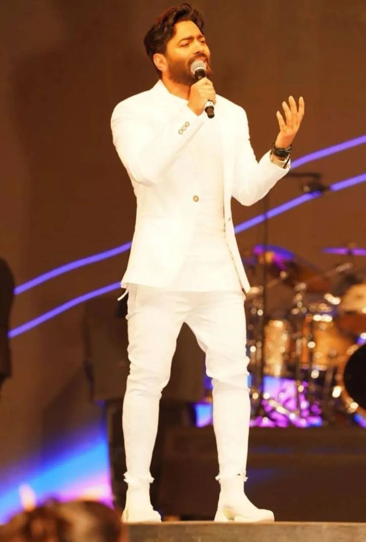 تامر حسني ببليزر باللون الأبيض مع بنطلون وتيشرت وحذاء رياضي باللون نفسه 