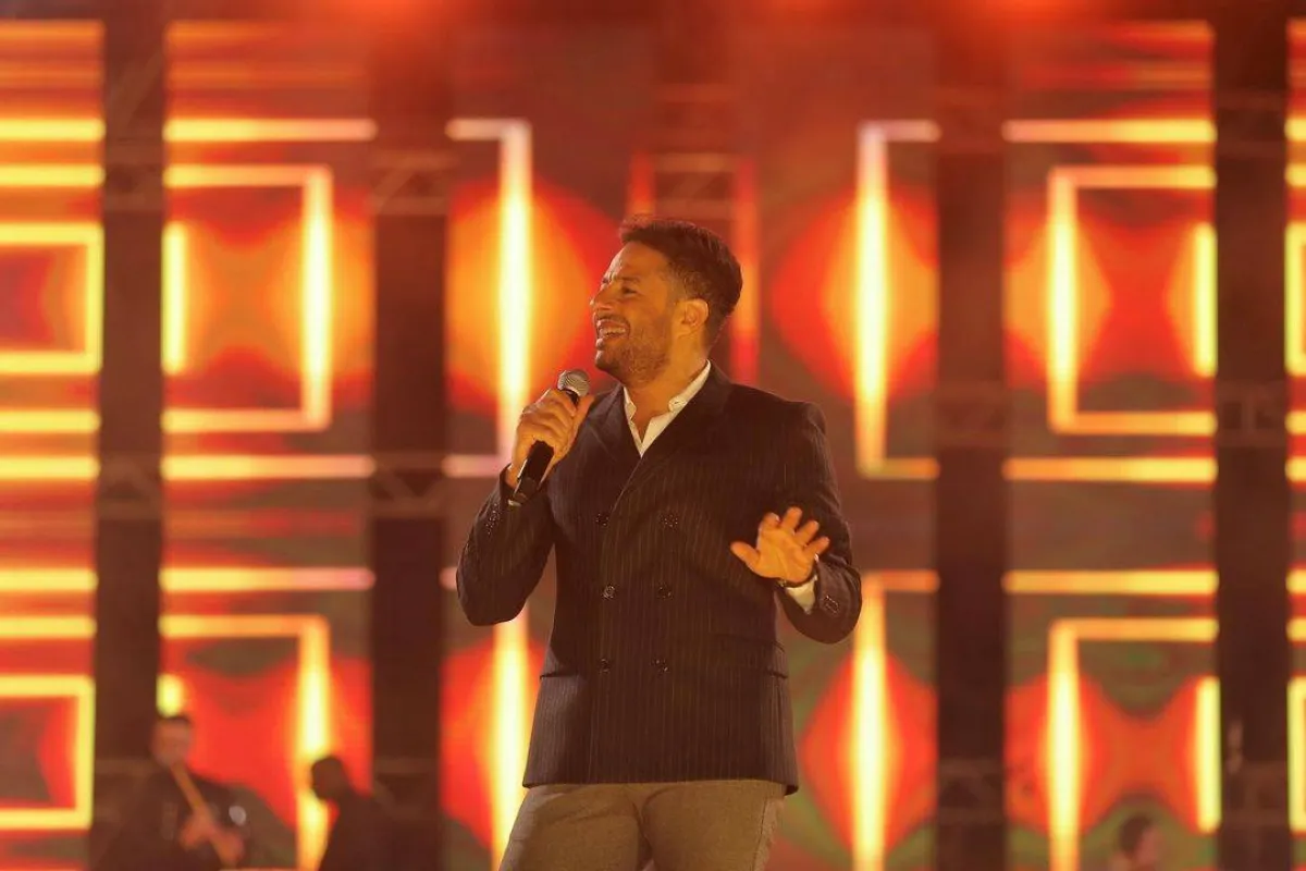 محمد حماقي ببليزر مقلَّم باللون الأسود وبنطلون باللون الرمادي الداكن