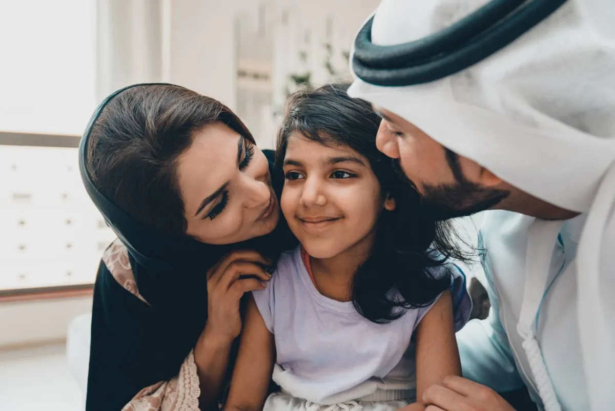 صورة لأبوين يقبلان ابنتهما