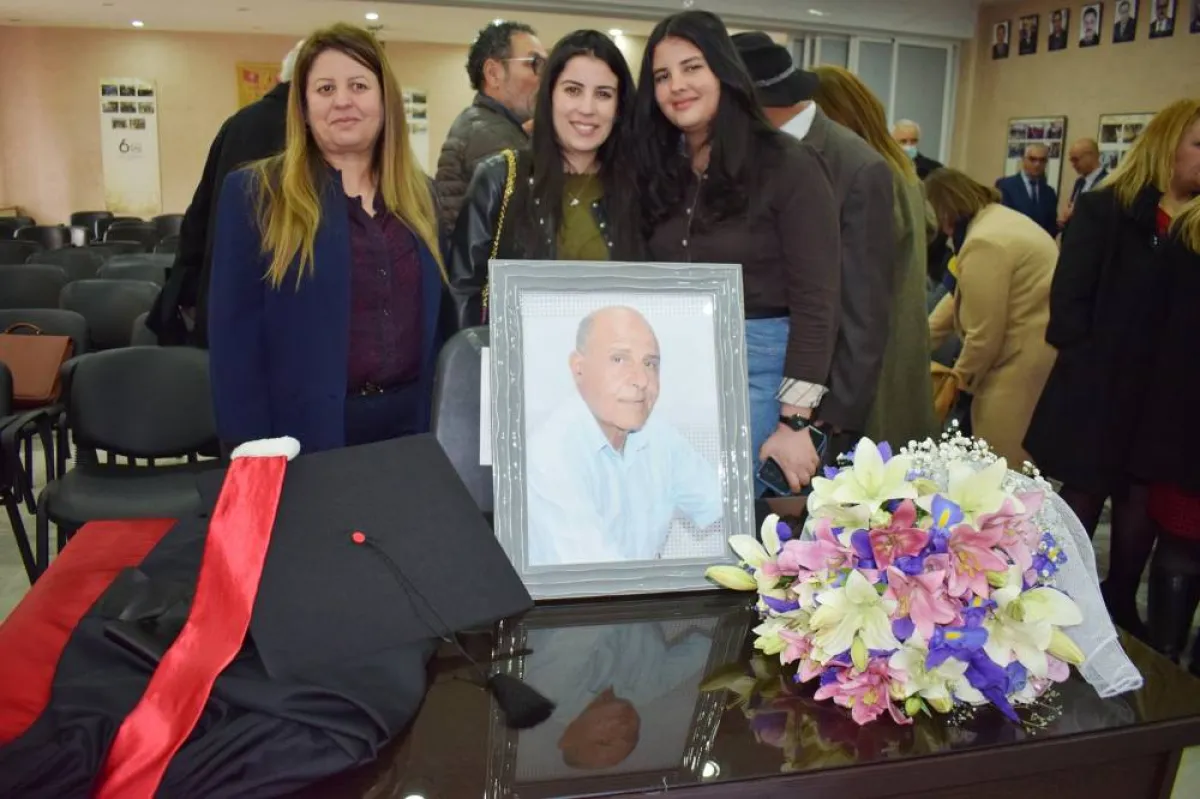 كرسي الفقيد وعليه صورته واكليل من الورد وحوله اسرة الاستاذ الراحل 