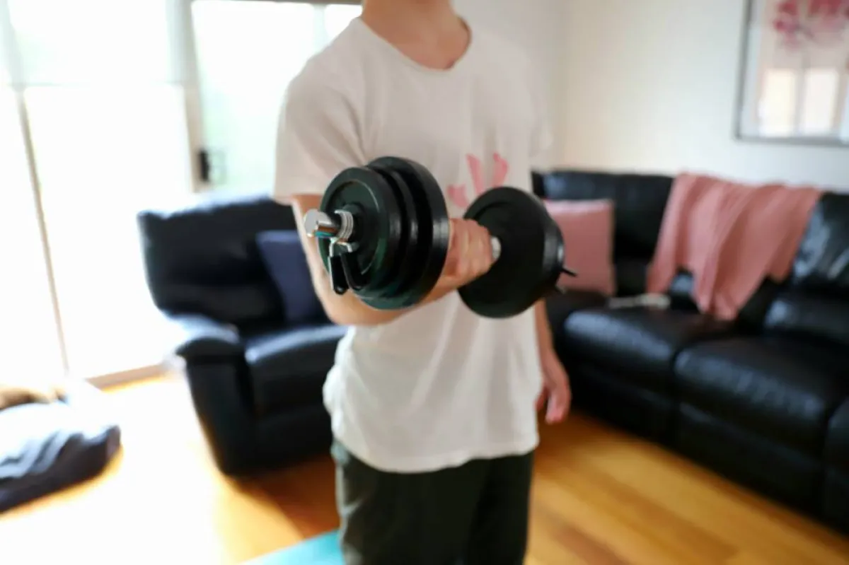 صورة لطفل يحمل وزناً ويمارس تمريناً لإطالة عضلات الظهر وتقويتها