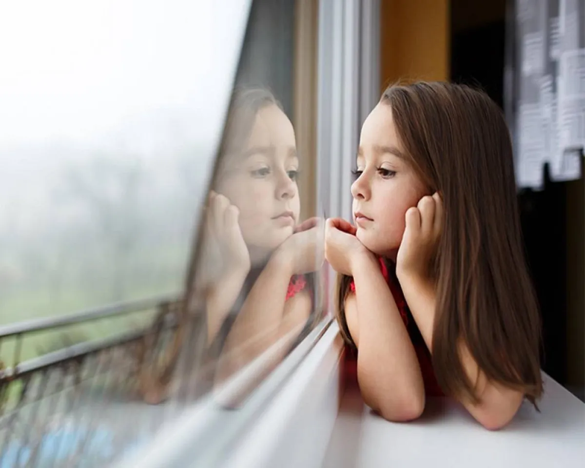 صورة لطفلة تنظر من النافذة