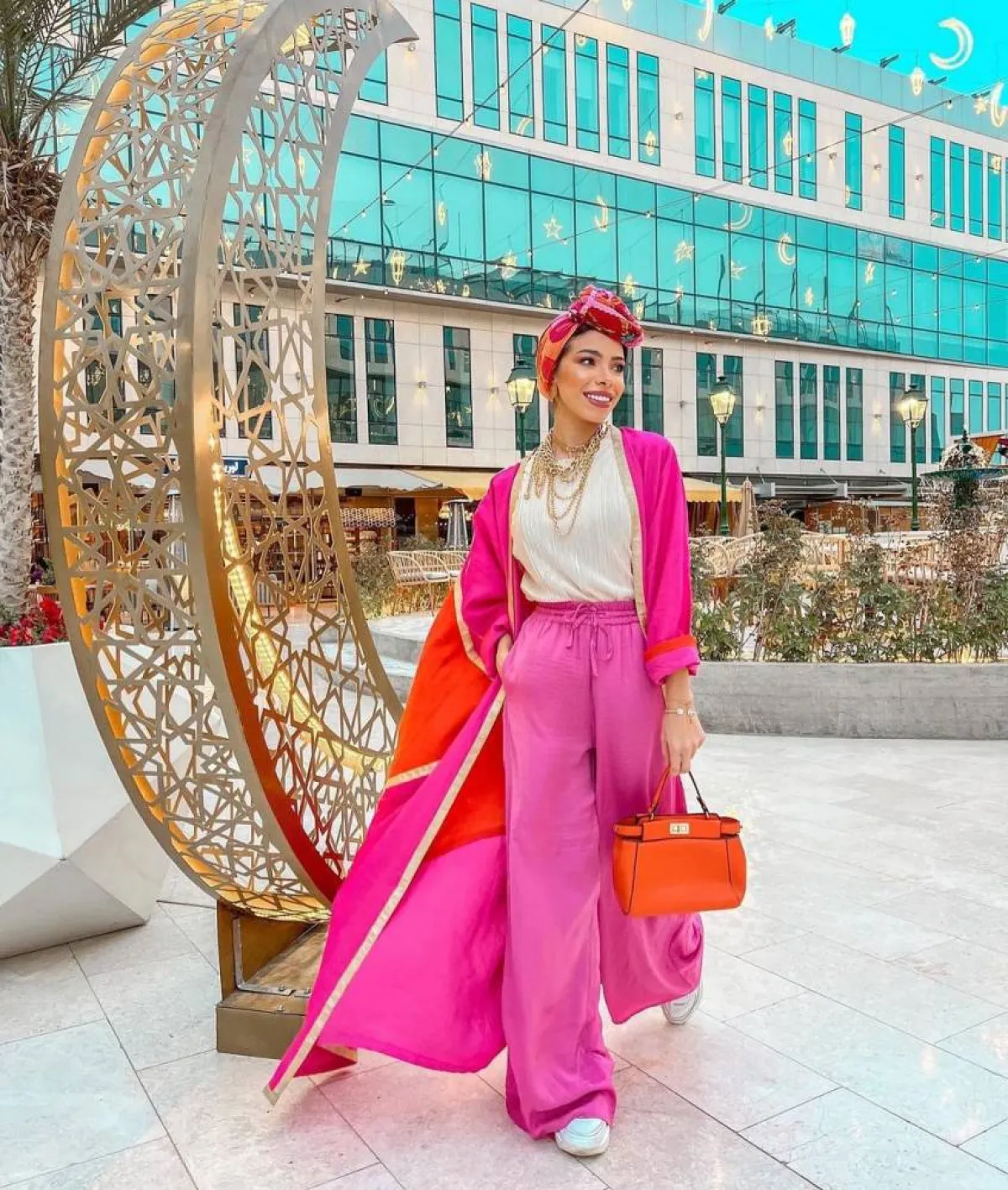 منة السُني بعباية مفتوحة باللونين البرتقالي والوردي وحقيبة صغيرة