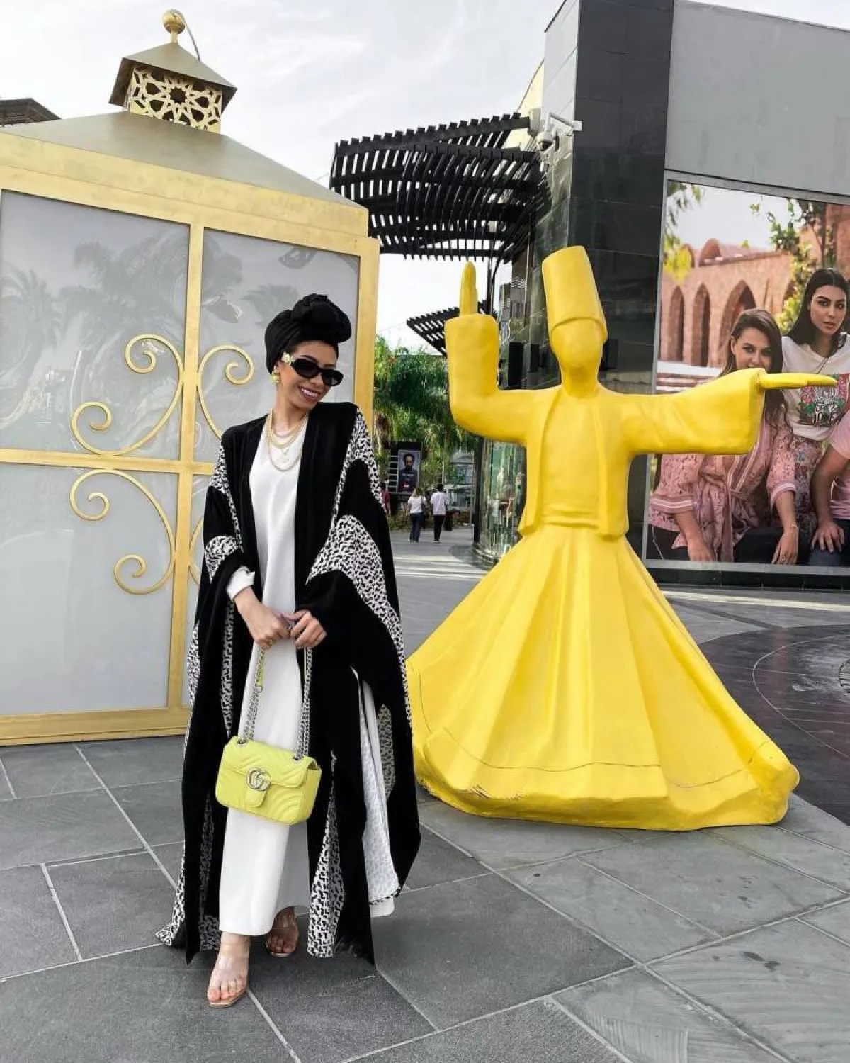 منة السُني بحقيبة صفراء وعباية باللونين الأبيض والأسود