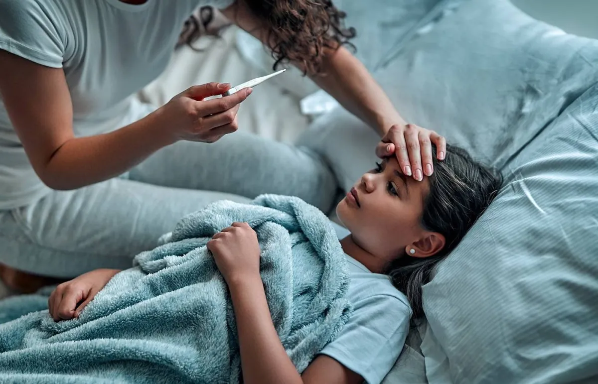 صورة لأم تقيس درجة حرارة طفلتها