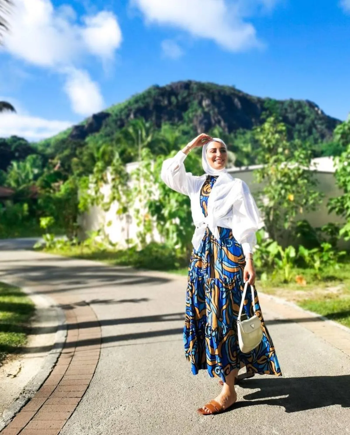 دلال الدوب بفستان معرق من البليسيه وحقيبة يد باللون الأبيض