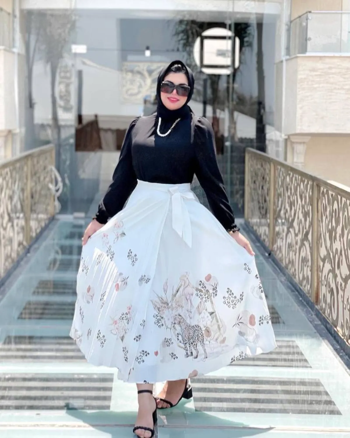 أمنية الجعفري بتنورة طويلة من البليسيه باللون الأبيض، وإيشارب أسود