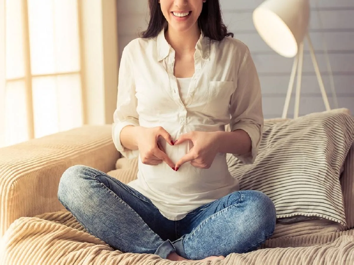 صورة لحامل تقوم برسم قلب بأيديها 