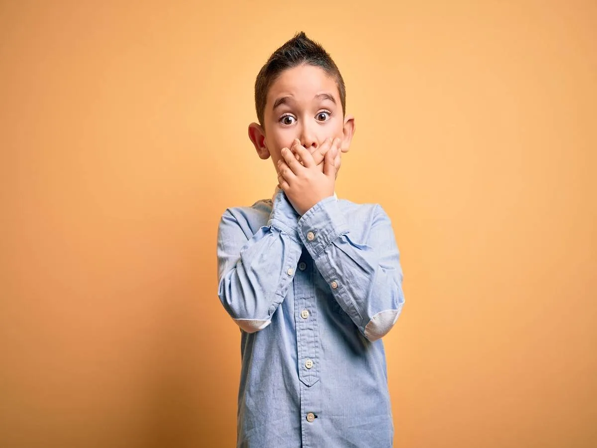 صورة لطفل يضع يديه على فمه