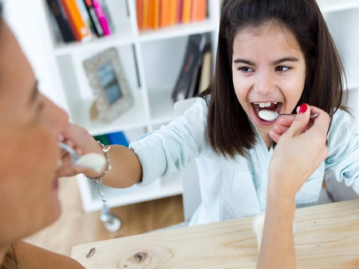 صورة لطفلة تتناول الزبادي مع والدتها