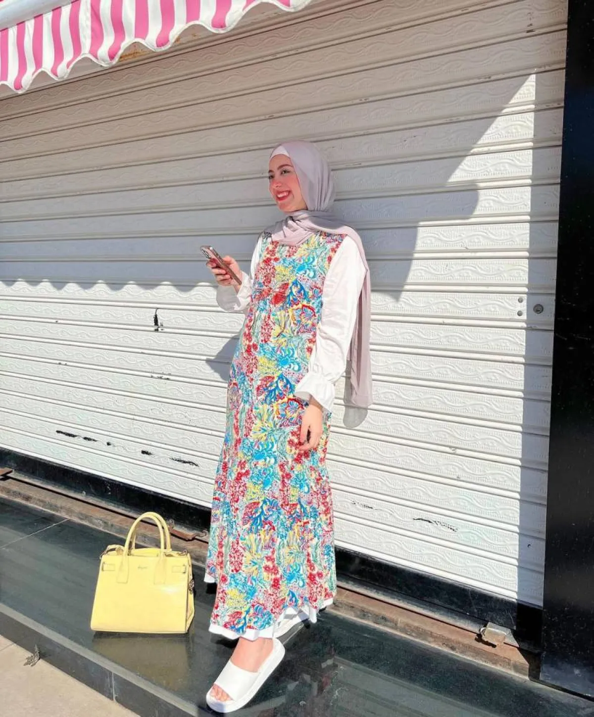 علا عبدالحميد بفستان ملون وإيشارب كشمير وحقيبة صفراء