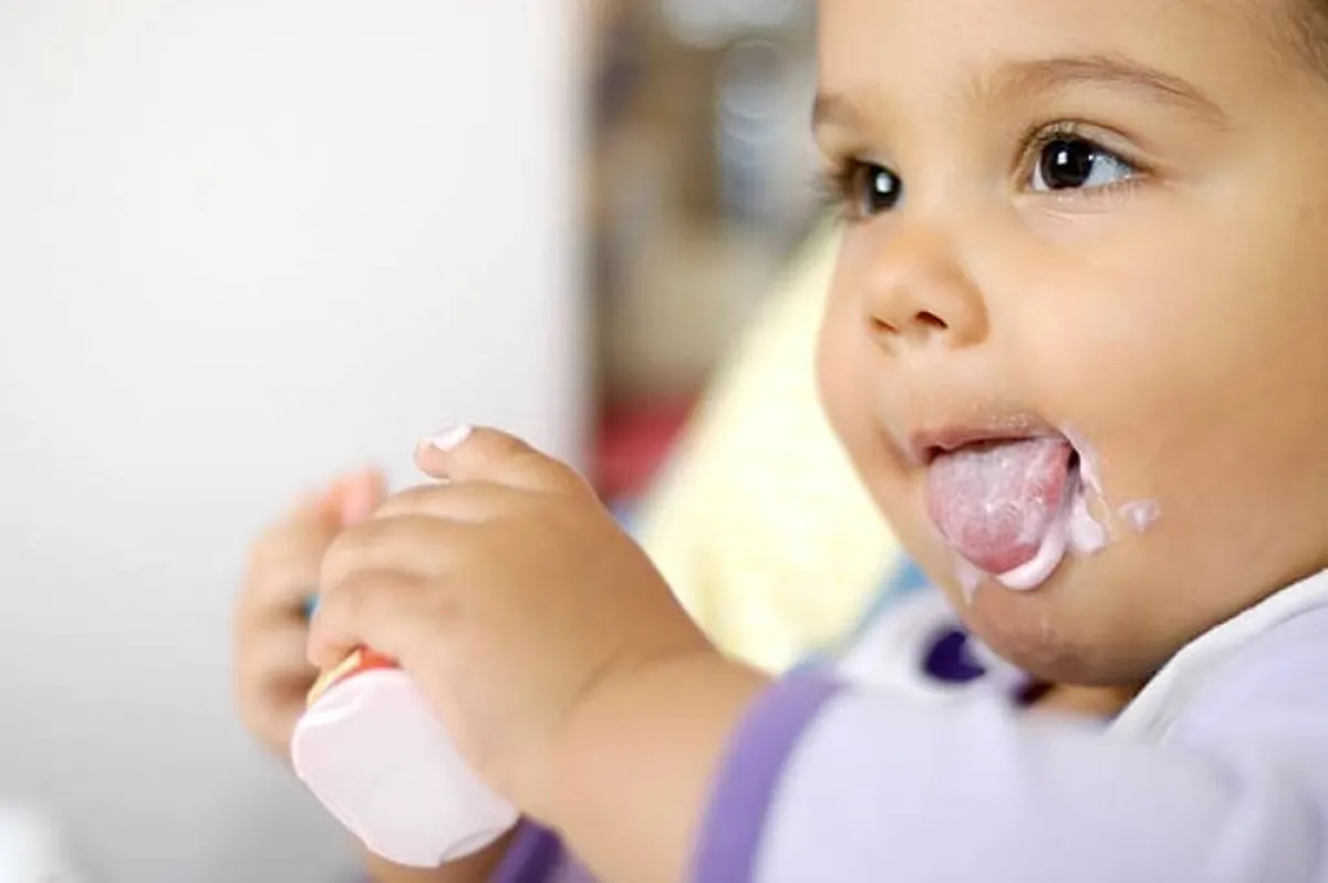 صورة لطفل رضيع يأكل اللبن الزبادي المضاف له السمسم المطحون