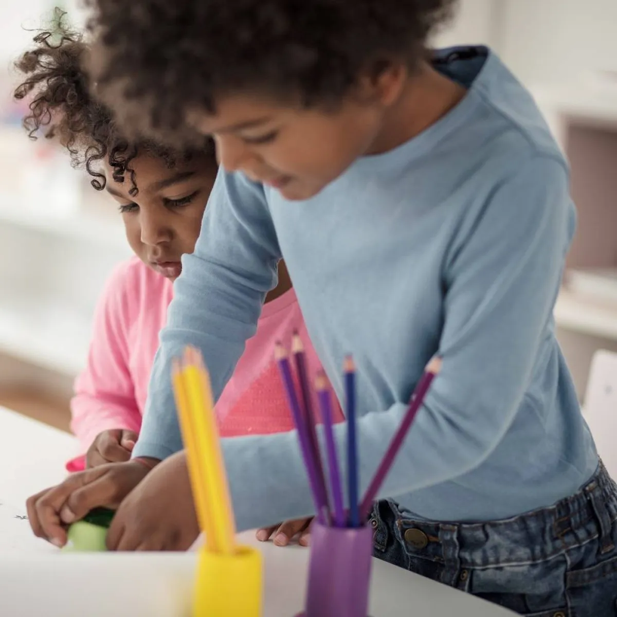 صورة لطفلين يلونان الورق