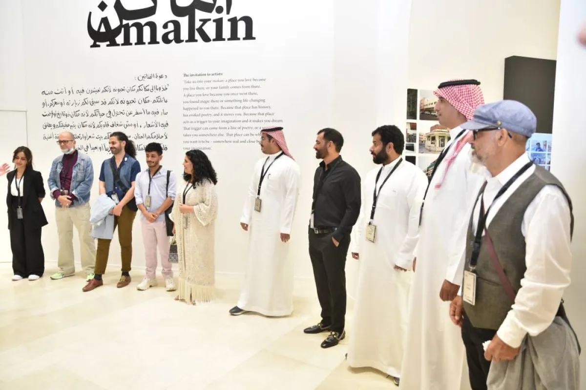 الرسامون المشاركون في المعرض في لقطة جماعية عند مدخل المعرض