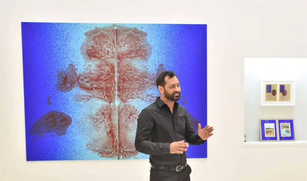 الفنان العالمي عمران قرشي يقف امام لوحته التي ارتبطت بالبحر