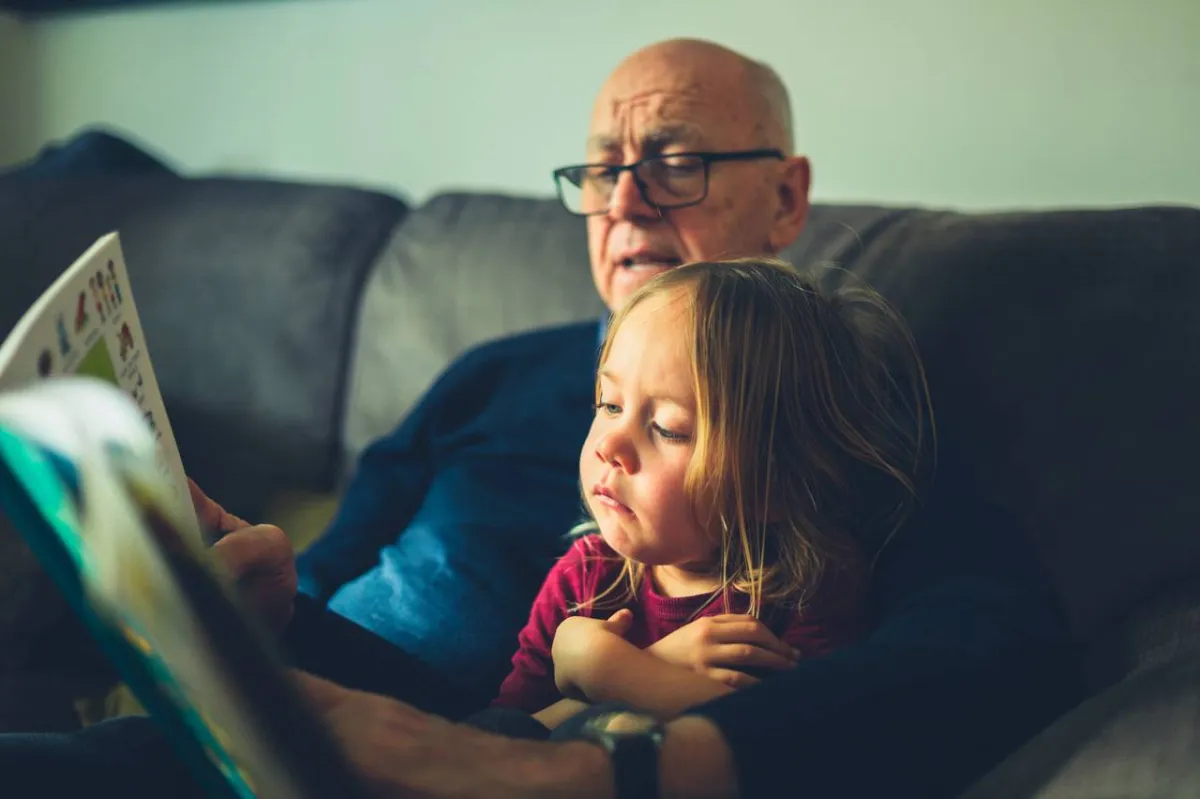 صورة جد يقرأ لحفيدته