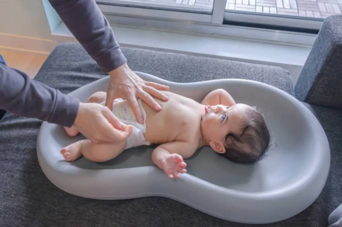 صورة لمولود يتم تغيير حفاضه وتنظيفه