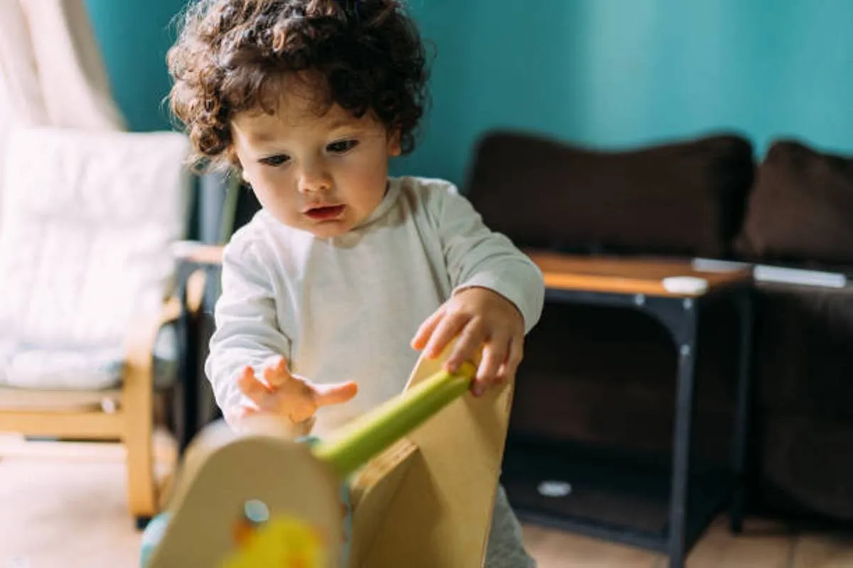 صورة لطفل يرتكز على مشاية ذات دفع أمامي