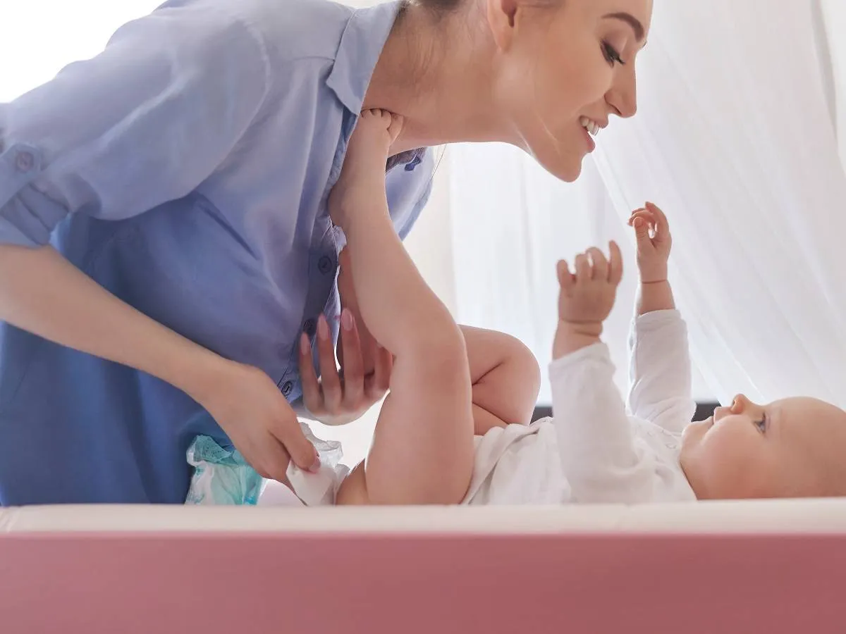 صورة لأم تغير الحفاض لطفلها