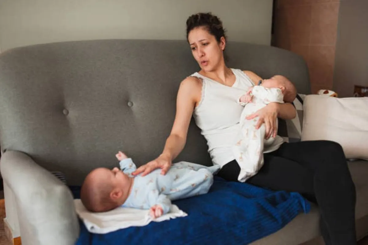 صورة لأم تعاني وهي تعتني بالتوأم