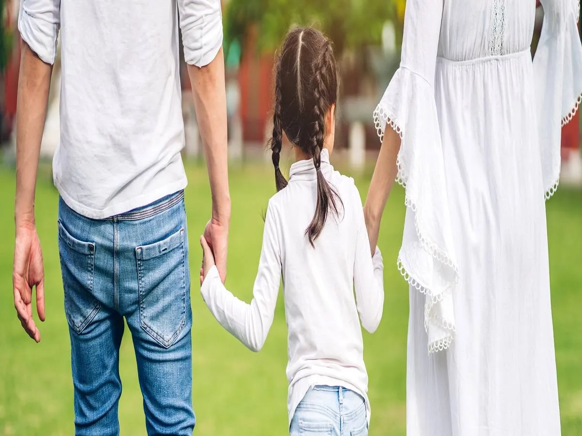 صورة لطفلة تمسك يدي والديها