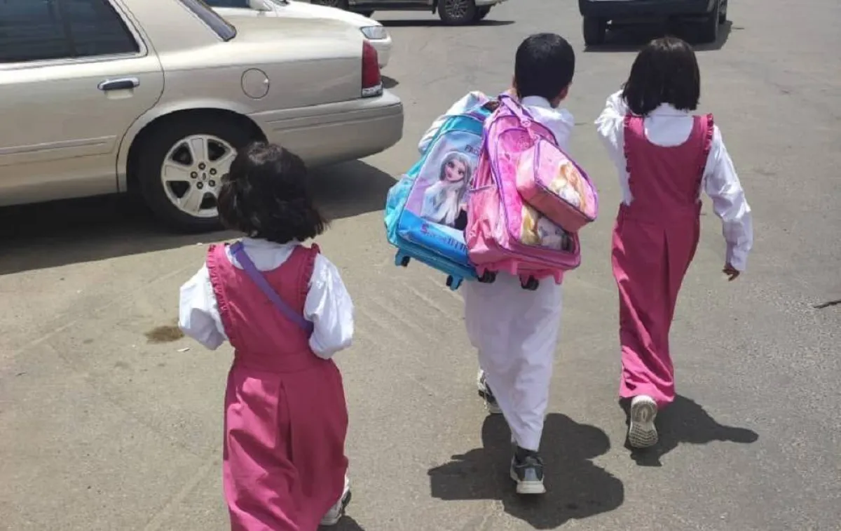 صورة الطفل مشعل يحمل حقيبة شقيقتيه