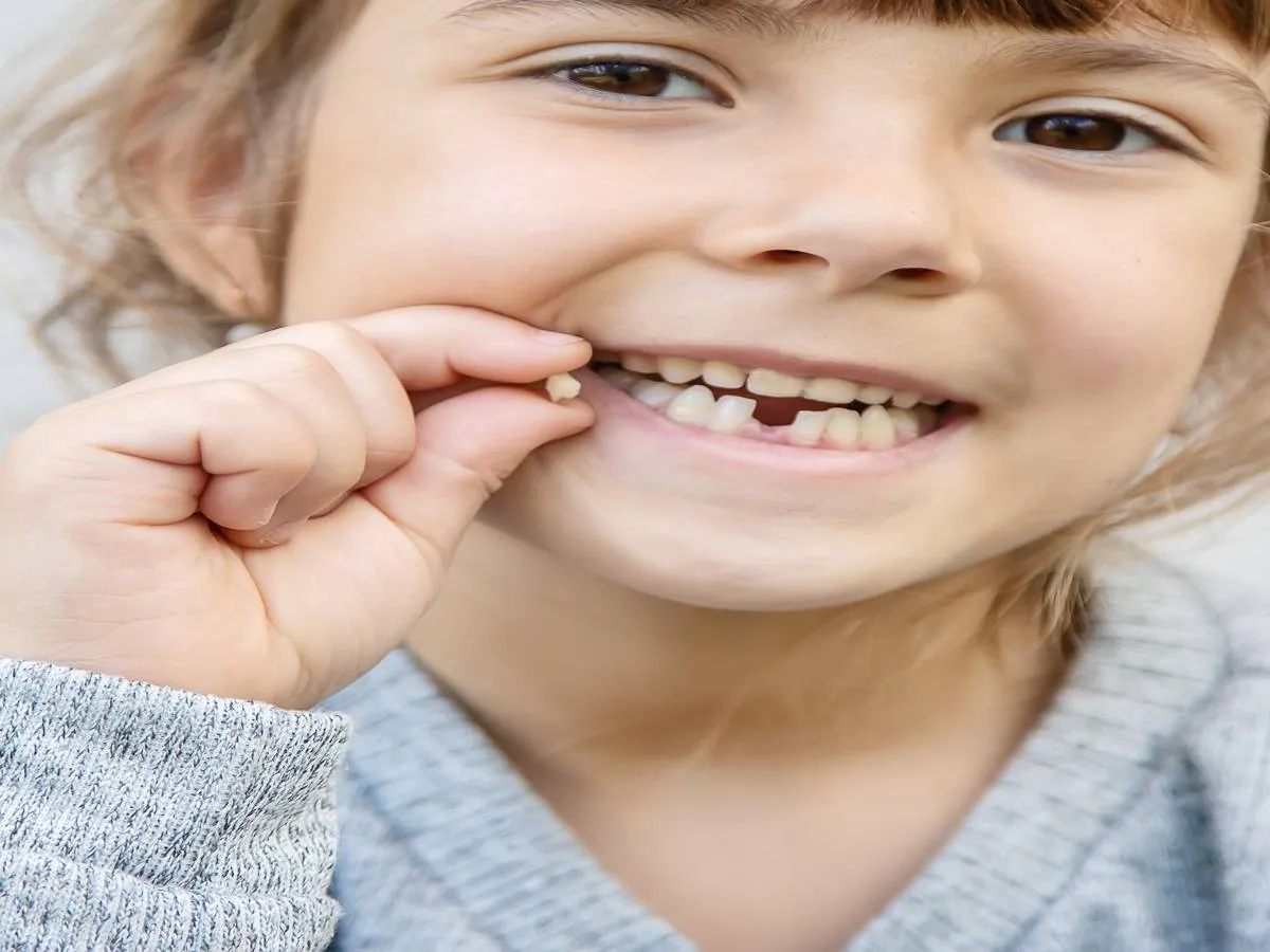 صورة لطفلة تحمل سن سقط من فمها
