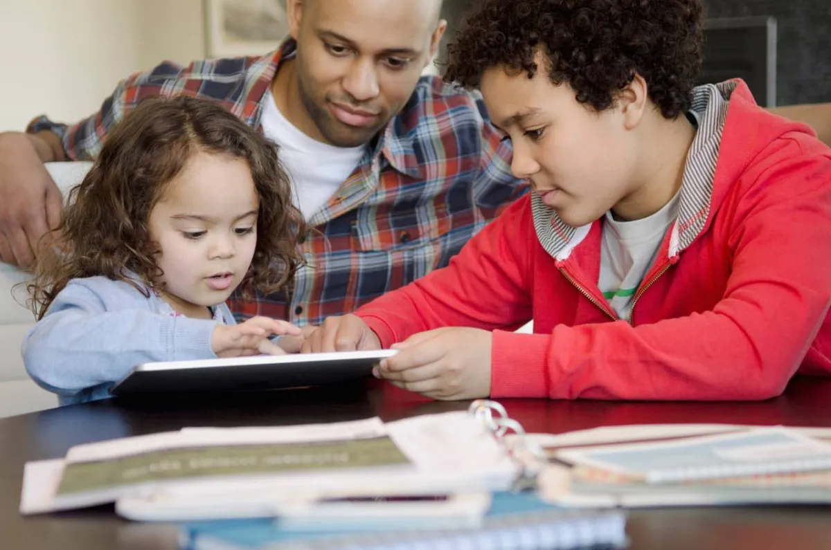 صورة لأب وشقيق يعلمان الأخت الصغرى