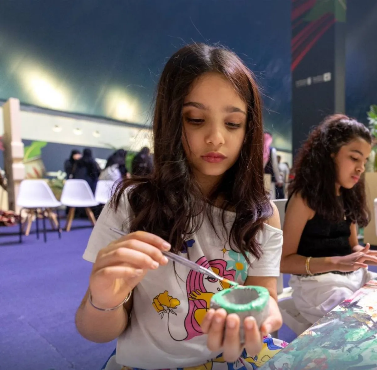 الأطفال يلونون الفناجيل الطينية - الصورة من حساب الفعاليات الثقافية على تويتر