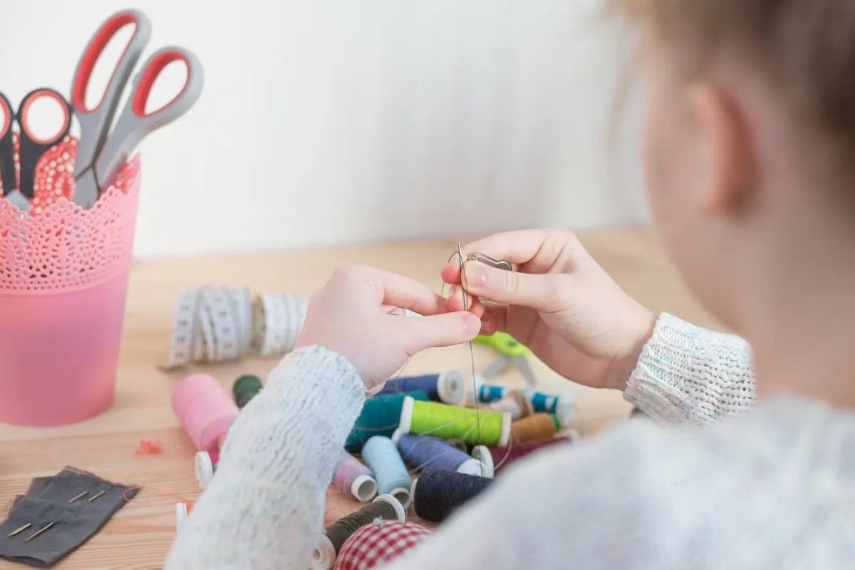 صورة لطفل تخيط ثوب الدمية