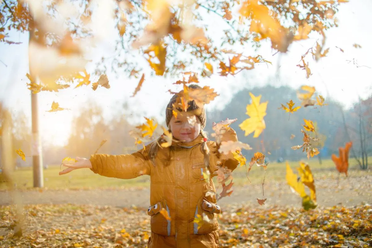 طفل يغني تحت أوراق الخريف
