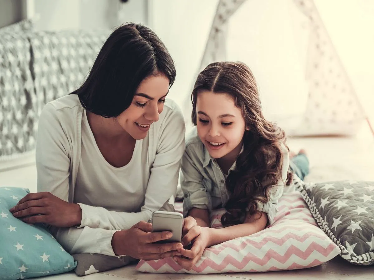 صورة لأم تنظر للهاتف مع ابنتها