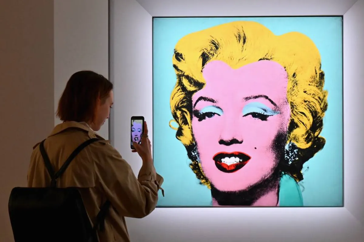 A woman takes a photo of Andy Warhol's 'Shot Sage Blue Marilyn' during Christie's 20th and 21st Century Art press preview at Christie's New York on April 29, 2022 in New York City. Angela Weiss / AFP