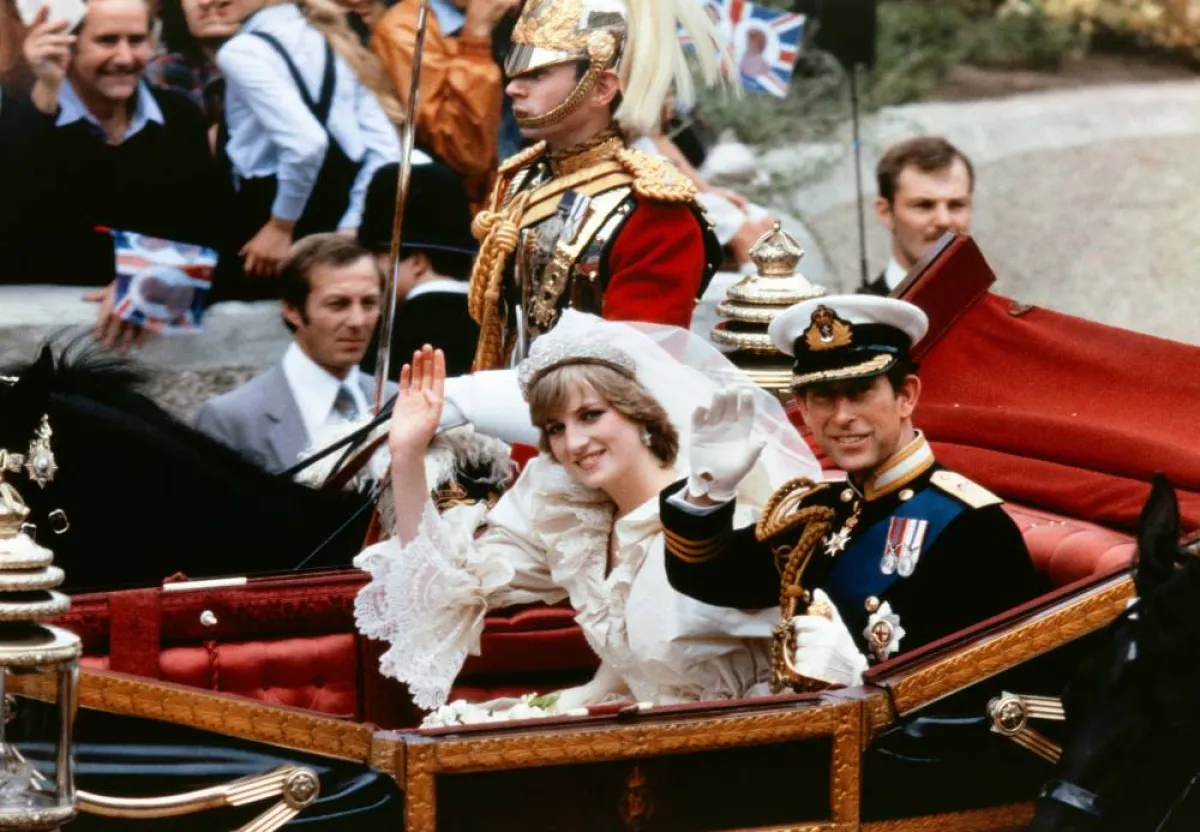 Lady Diana and Charles, Prince of Wales, acknowledge the crowd as they arrive in a carriage at Buckingham Palace on July 29, 1981, after their wedding in St Paul's Cathedral. POOL / AFP