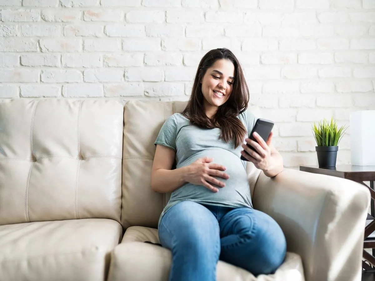 صورة لامرأة حامل تنظر لشاشة الهاتف 