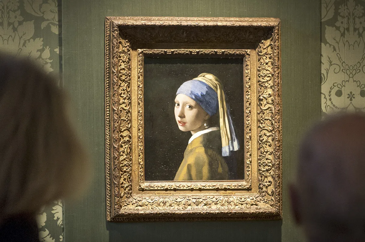 Visitors looks at the Johannes Vermeer's painting "Girl with a Pearl Earring" at the Mauritshuis museum in The Hague, 27 October 2022. - Dutch police arrested three people after climate activists targeted Johannes Vermeer's painting "Girl with a Pearl Earring". (Photo by Lex van Lieshout / ANP / AFP) / Netherlands OUT