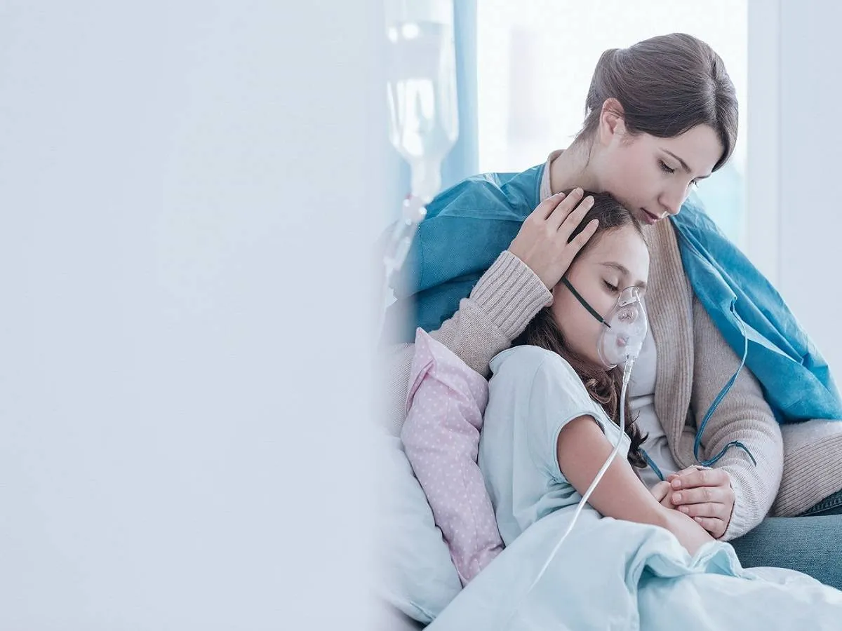 صورة لأم تحتضن طفلتها وهي تتلقى العلاج