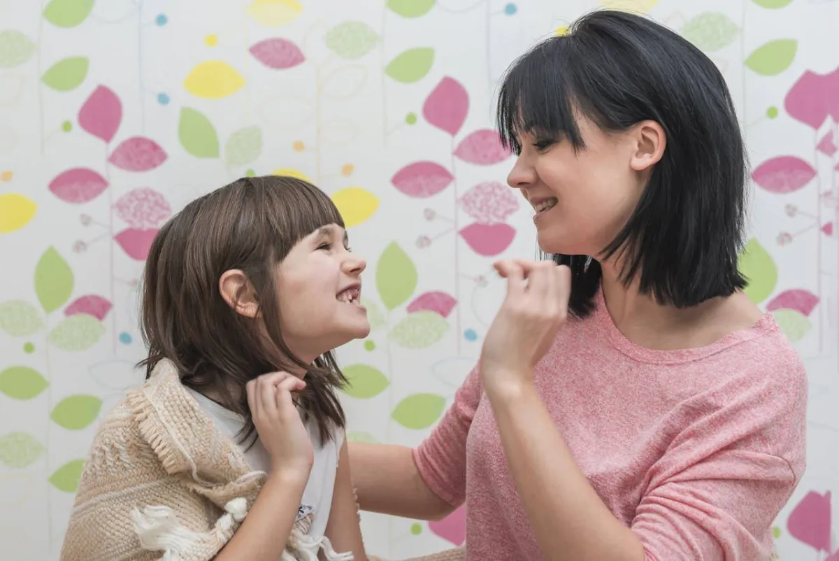 صورة أم تعلم طفلته طريقة نطق الحرف