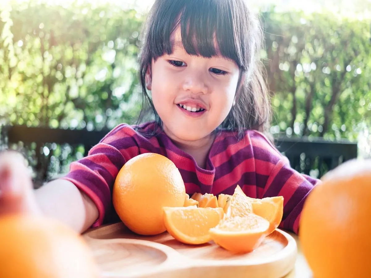 صورة لطفلة تتناول البرتقال