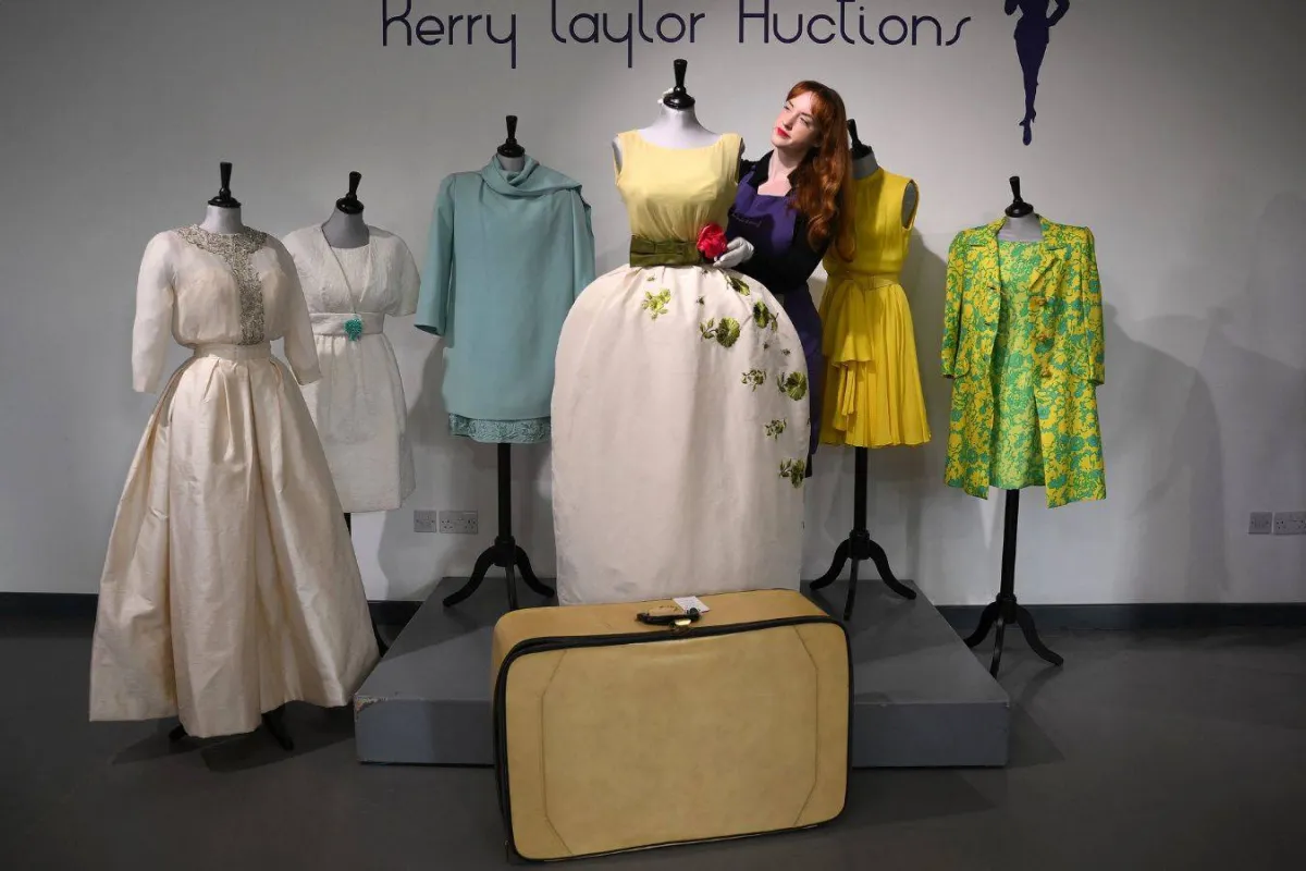 An employee poses with a Christian Dior dress worn by actress Elizabeth Taylor, and recently discovered with other dresses in a suitcase, ahead of their sale at Kerry Taylor Auctions, in London on November 25, 2022. A "lucky charm" Christian Dior dress worn by Elizabeth Taylor on the night she won best actress at the 1961 Oscars is to be sold at auction on December 6, 2022, after being stored in a suitcase in London for over 50 years. Daniel LEAL / AFP