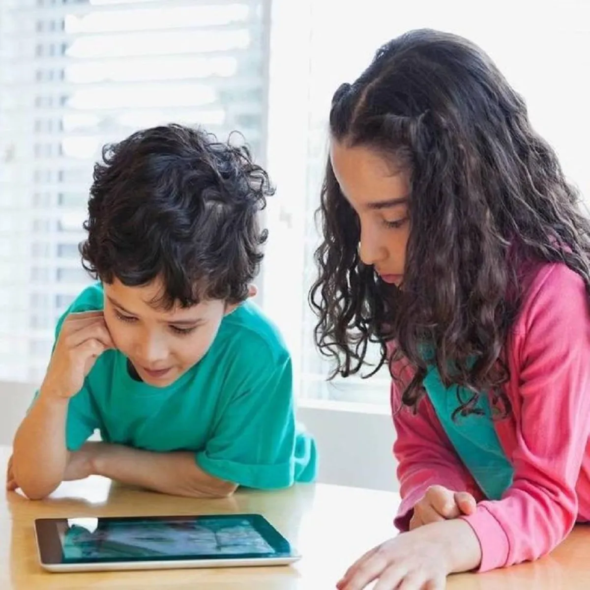 صورة لطفلين يتابعان بشغف الآيباد
