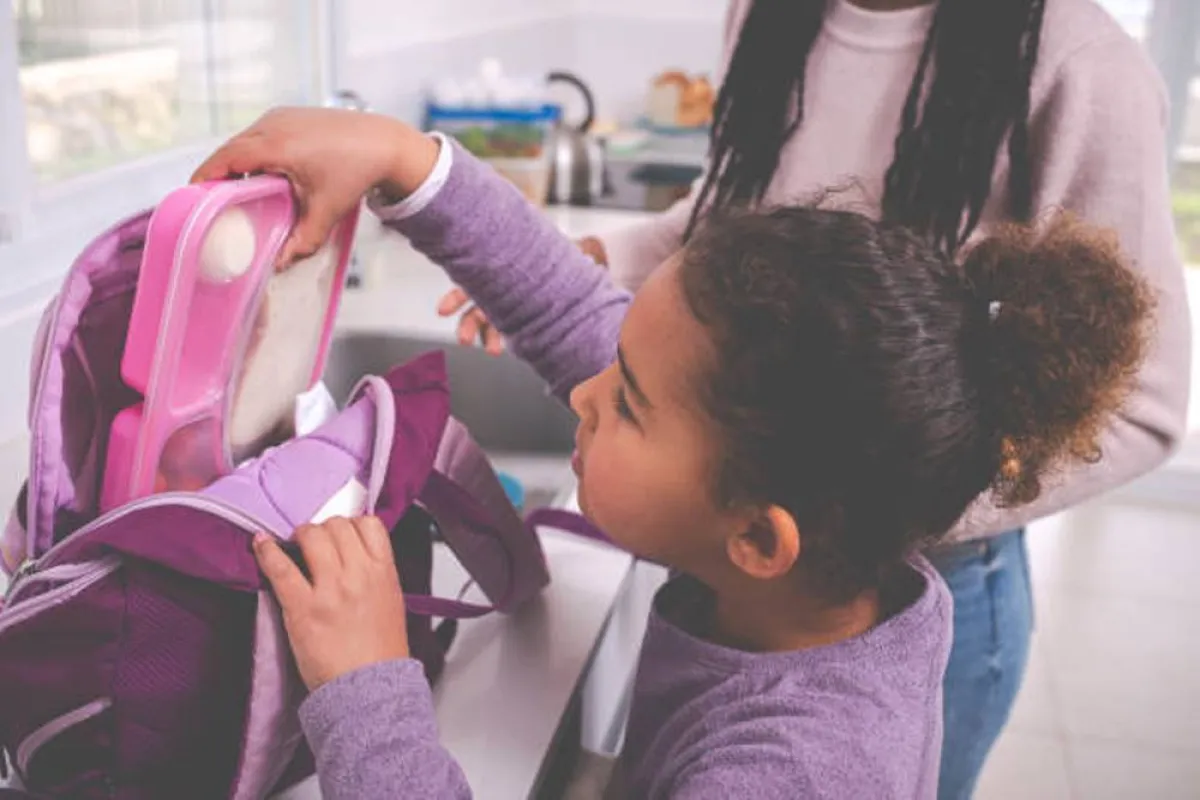 صورة لطفلة تضع صندوق طعام المدرسة في الحقيبة